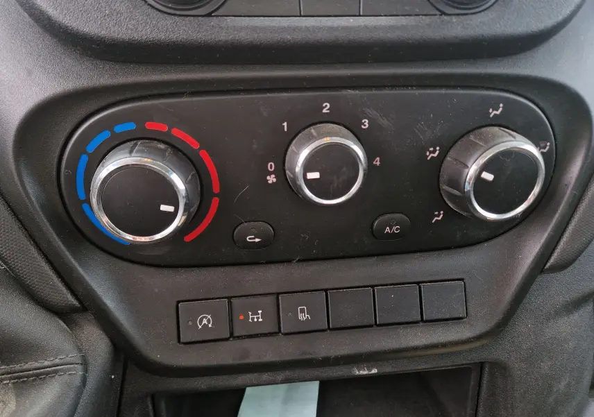 Gros plan sur les commandes de climatisation et ventilation noires du tableau de bord d'un Iveco Daily Chassis Cabine blanc.