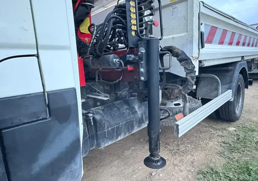 Détail côté gauche d’une benne blanche Iveco Daily 35C14 avec grue Palfinger et stabilisateur déployé.