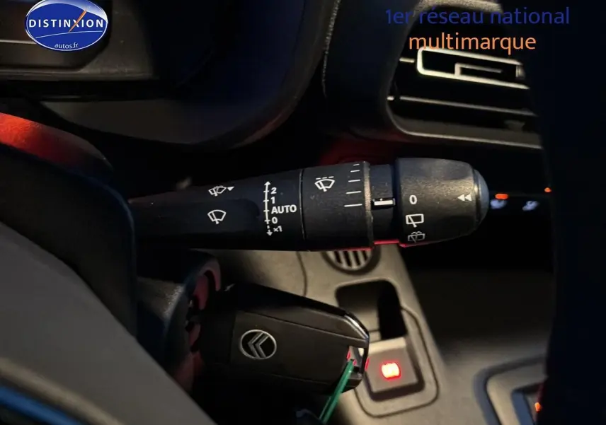 Gros plan sur la manette d'essuie-glace et la clé de contact dans l'habitacle du Citroën Berlingo Fourgon blanc.