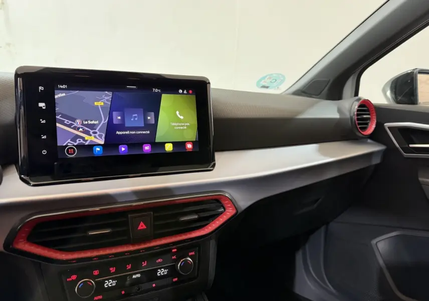 Vue intérieure côté passager du tableau de bord de la SEAT Ibiza blanc, avec écran tactile et aérateurs rouges.