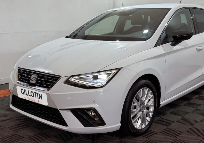 SEAT Ibiza 1.0 TSI 110 FR blanc vue 3/4 avant droit, phares LED allumés et jantes alliage distinctives.