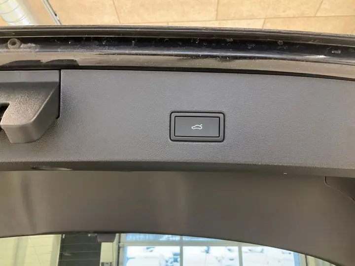 Bouton d'ouverture électrique du coffre sur la partie intérieure du hayon d'un Volkswagen T-Roc noir intense.