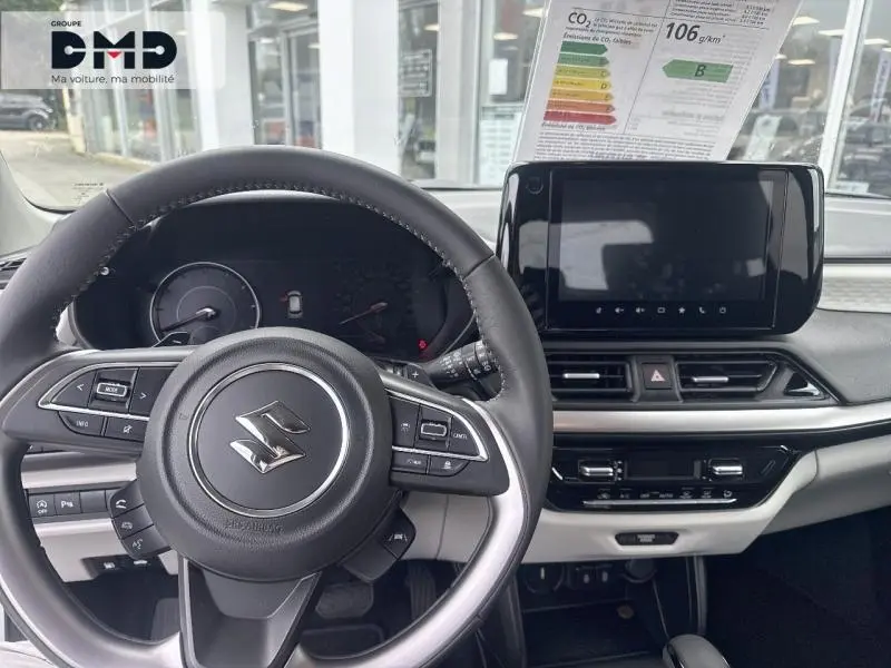 Vue intérieure centrée sur le volant cuir multifonction et l’écran tactile du tableau de bord de la Suzuki Swift blanche.