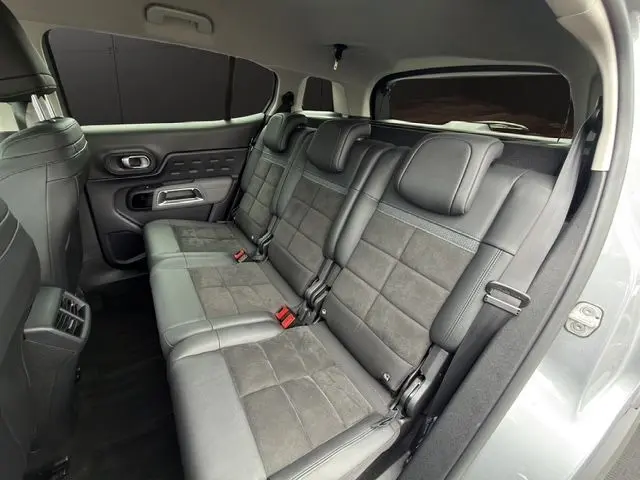 Vue intérieure côté droit des sièges arrière en tissu et cuir gris du Citroën C5 Aircross gris acier, avec appuie-têtes et ceintures visibles.