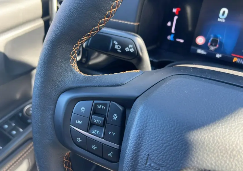 Gros plan sur le volant cuir noir avec surpiqûres marron et commandes multifonctions du Ford Ranger Wildtrak 2026.
