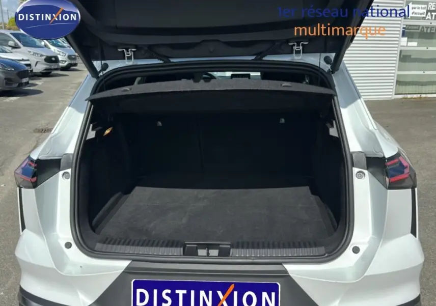 Vue arrière ouverte du coffre d'une Renault SYMBIOZ blanc, mettant en valeur l'espace de chargement vide et les feux arrière distinctifs.