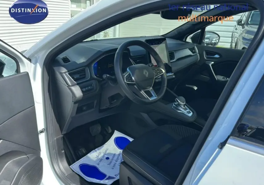 Intérieur avant gauche du Renault Symbioz blanc 2025, volant multifonction et écran tactile central visible.