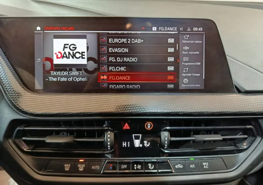 Vue rapprochée du tableau de bord de la BMW Série 1 noire, affichant l'écran tactile multimédia et la console de climatisation.