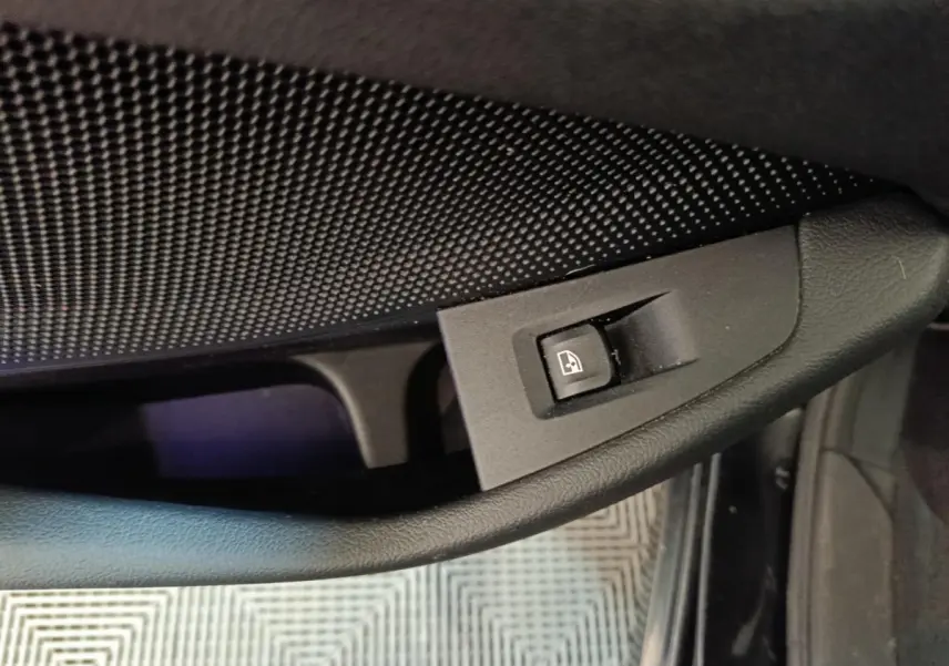 Gros plan sur la commande de lève-vitre côté conducteur de la BMW Série 1 118i noire, intérieur sombre.