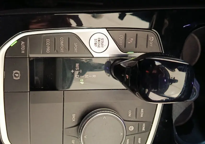 Vue rapprochée du sélecteur de vitesses et molette de contrôle central noir brillant dans une BMW Série 1 118i Edition Sport 2023.