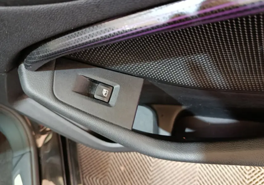 Détail de la commande de lève-vitre côté conducteur sur la porte intérieure noire d’une BMW Série 1 118i Edition Sport 2023.