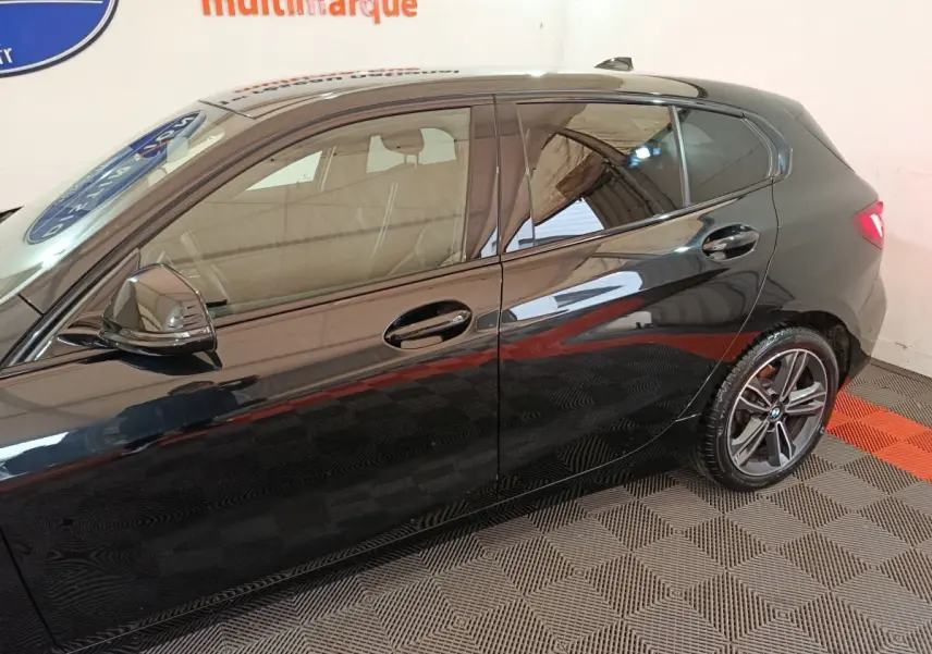 Vue latérale côté gauche d'une BMW Série 1 118i Edition Sport noire avec jantes alliage et rétroviseurs ton caisse.