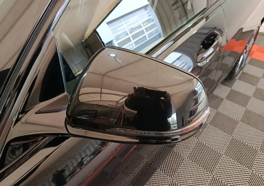 Rétroviseur côté gauche noir brillant d’une BMW Série 1 118i Edition Sport 2023, vue rapprochée en intérieur.