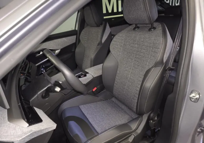 Vue intérieure côté conducteur du Peugeot 3008 gris 2025, sièges tissu gris et cuir noir avec surpiqûres quartz.