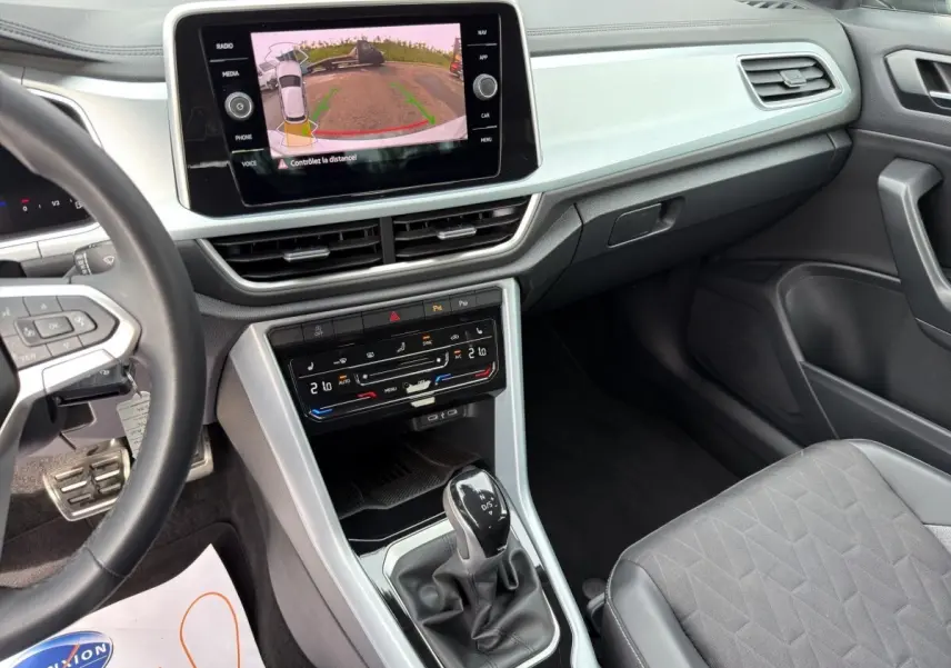 Vue intérieure côté conducteur du Volkswagen T-Roc 2025 avec écran tactile affichant la caméra de recul et levier de vitesse DSG.