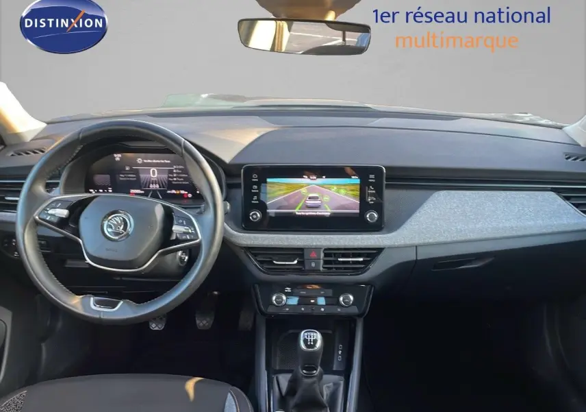 Vue intérieure frontale du tableau de bord du Skoda Kamiq 2024 gris graphite, avec volant multifonction et écran tactile central.