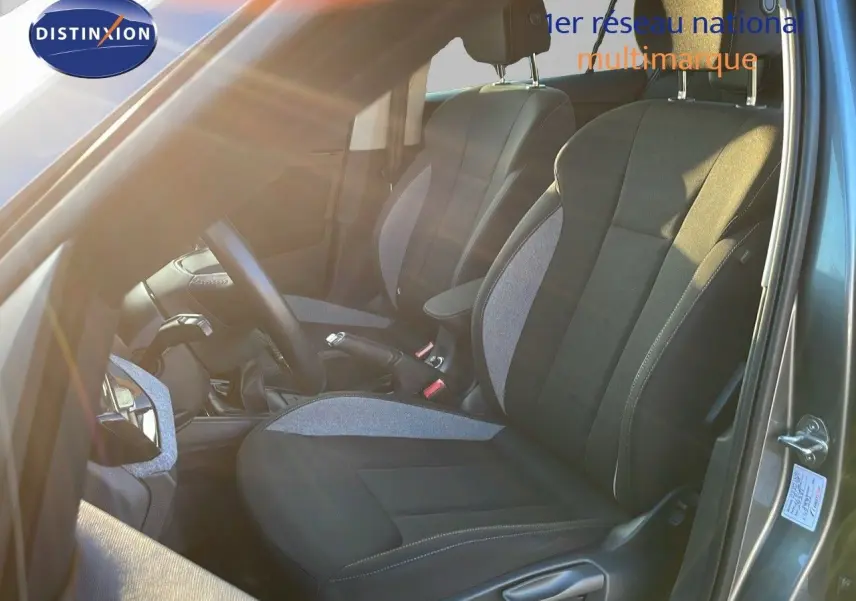 Vue intérieure côté conducteur du Skoda Kamiq gris graphite métal 2024, montrant les sièges avant en tissu bicolore et le levier de vitesses manuel.