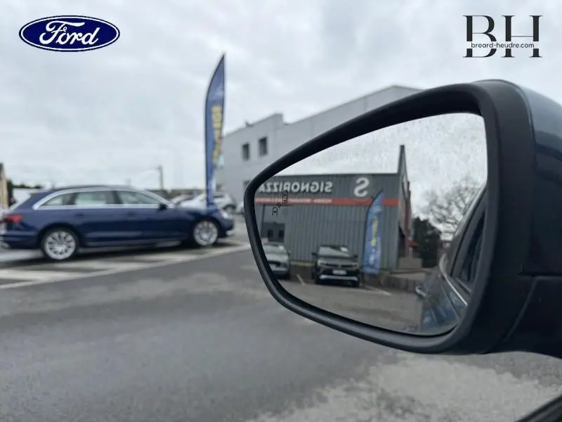 Vue latérale gauche d'une Ford Focus SW bleu azur métallisé garée, avec rétroviseur extérieur en premier plan.