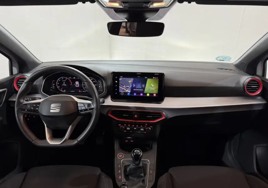 Vue intérieure frontale du tableau de bord de la SEAT Ibiza blanc avec volant cuir alu et écran tactile central.