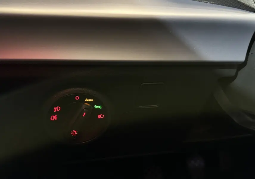 Gros plan sur le bouton de commande des phares dans l’habitacle sombre d’une SEAT Ibiza blanche 2024.