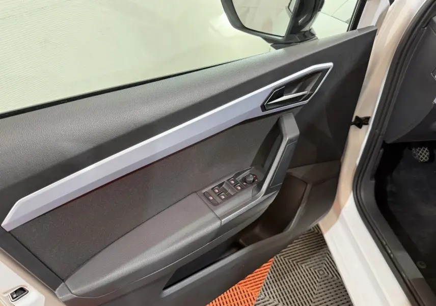 Vue rapprochée de la porte avant gauche blanche d’une SEAT Ibiza 2024 avec commandes électriques et poignée alu.