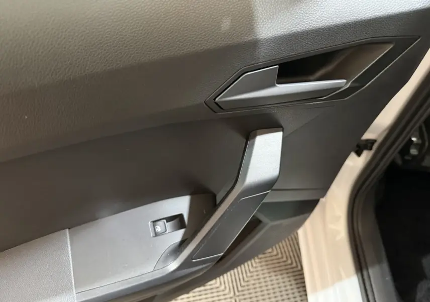 Gros plan sur la poignée intérieure côté conducteur de la SEAT Ibiza blanche, avec bouton de verrouillage des vitres.