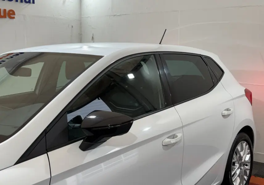 Vue côté gauche d'une SEAT Ibiza blanche 2024 avec rétroviseur noir et jantes alliage visibles en intérieur.