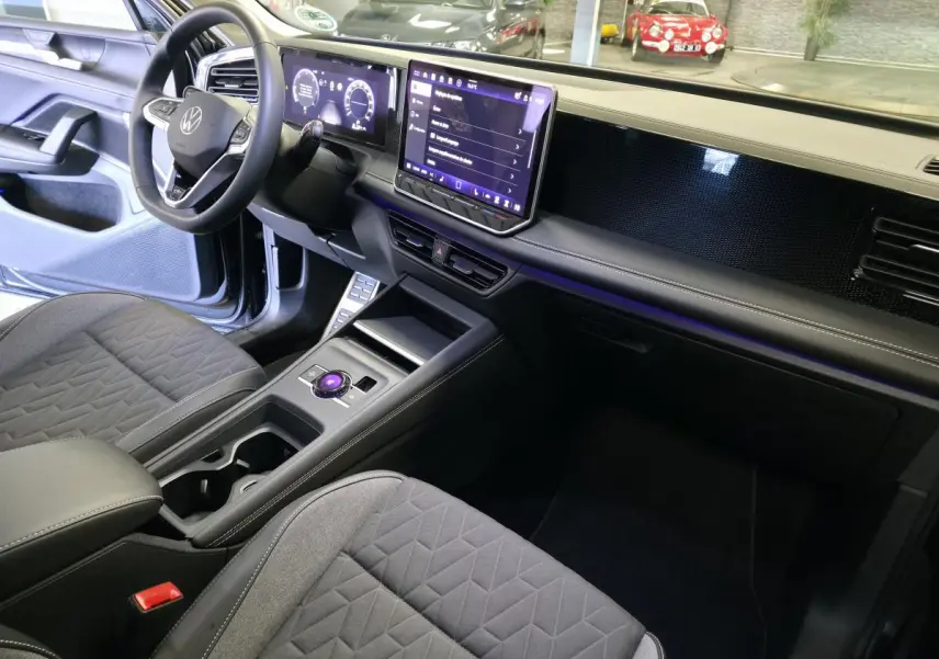 Intérieur avant droit du Volkswagen Tiguan 2025 noir, tableau de bord numérique et écran tactile central lumineux.