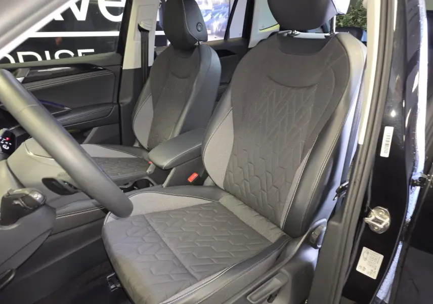 Vue intérieure côté avant droit du Volkswagen Tiguan 2025 noir, sièges tissu gris avec surpiqûres géométriques.