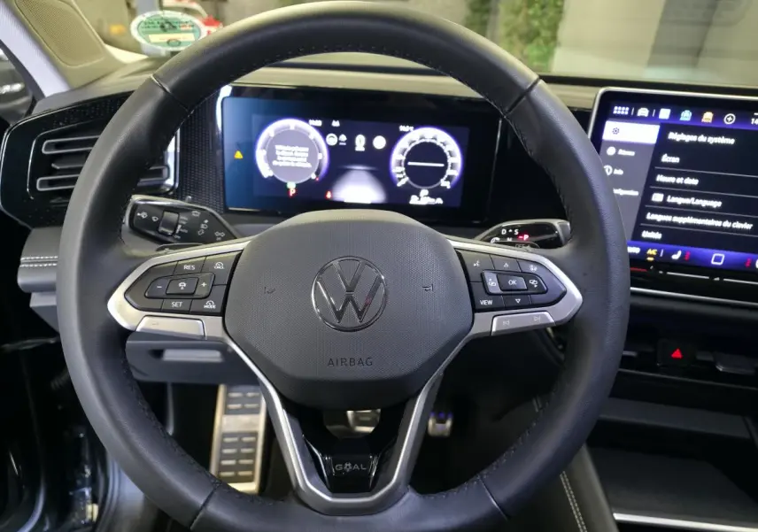 Vue rapprochée du volant en cuir noir du Volkswagen Tiguan 2025 avec tableau de bord numérique et écran tactile.