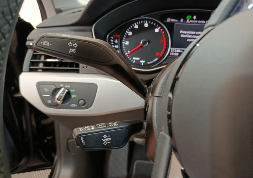 Gros plan sur le volant noir et les commandes au volant de l'Audi A4 35 TFSI 2024, avec tableau de bord digital visible.