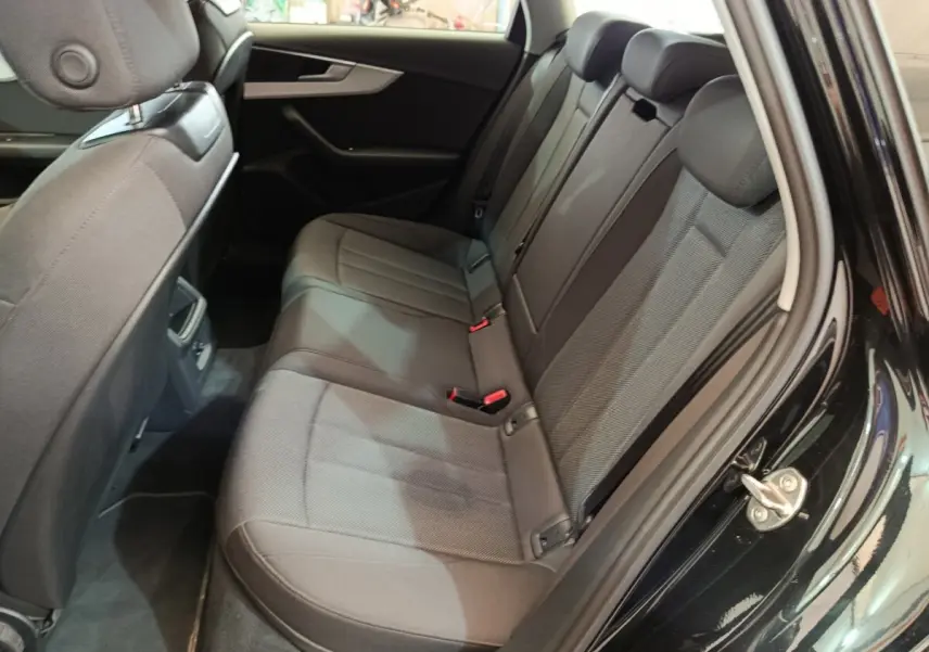 Vue côté droit de la banquette arrière noire de l'Audi A4 35 TFSI 2024 avec sièges tissu et ceintures visibles.