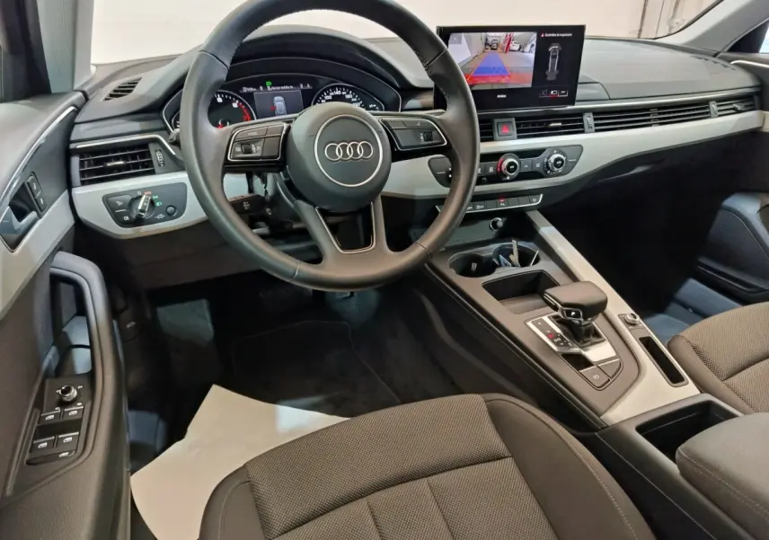 Intérieur Audi A4 35 TFSI 2024 vu côté conducteur, volant cuir, écran tactile avec caméra de recul, finition noire.