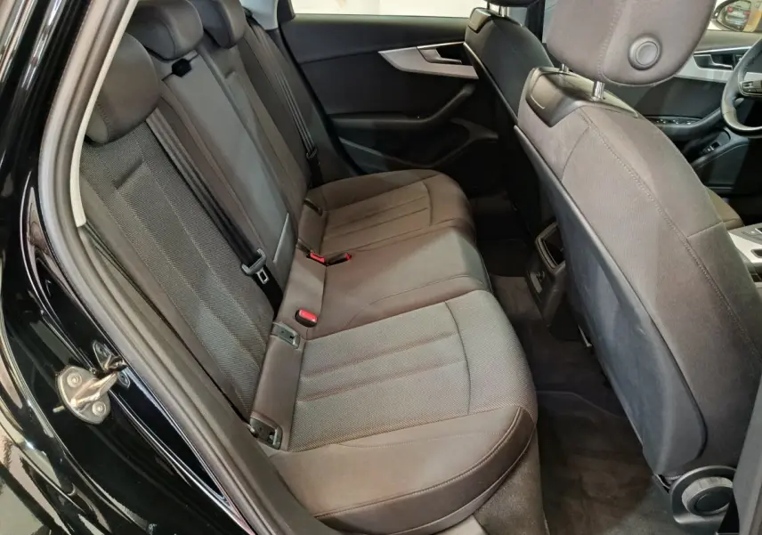 Vue intérieure côté gauche des sièges arrière en tissu gris foncé de l'Audi A4 35 TFSI Business Line noire de 2024.