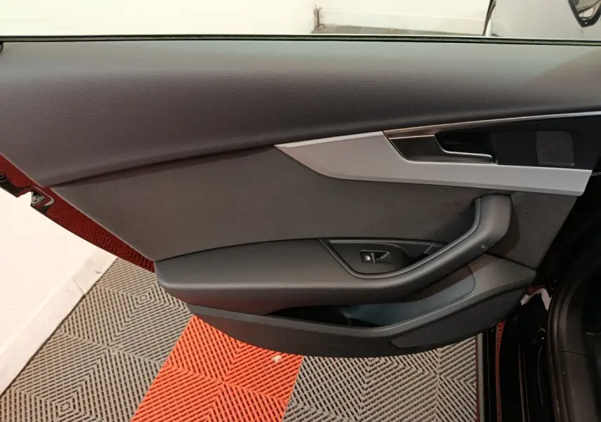 Vue du panneau de porte côté gauche de l'Audi A4 35 TFSI noir, avec poignée et commande de vitre électrique.