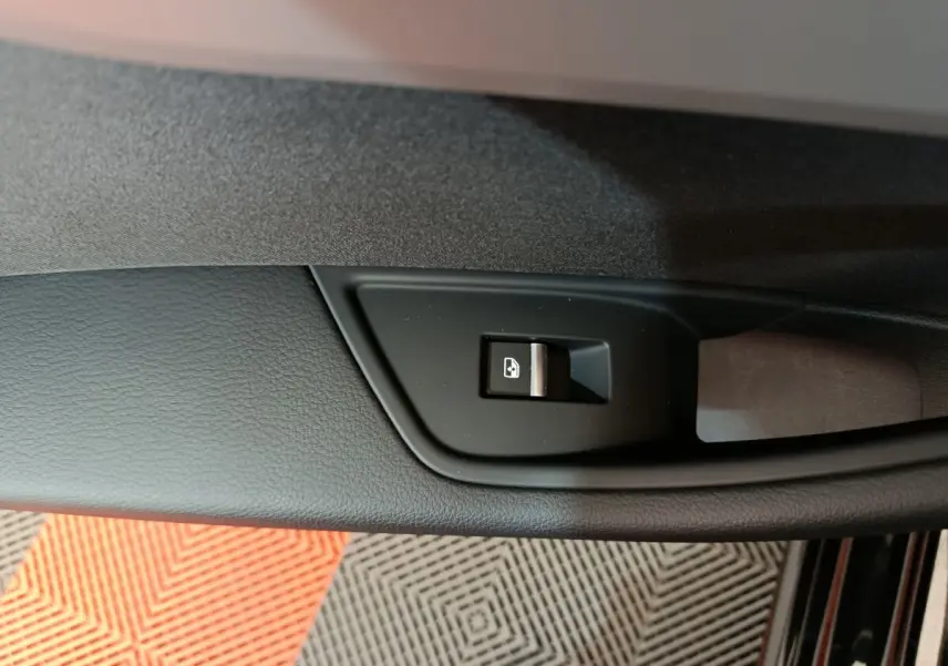 Gros plan sur le bouton de commande de vitre côté gauche dans une Audi A4 noire 2024, finition Business Line.