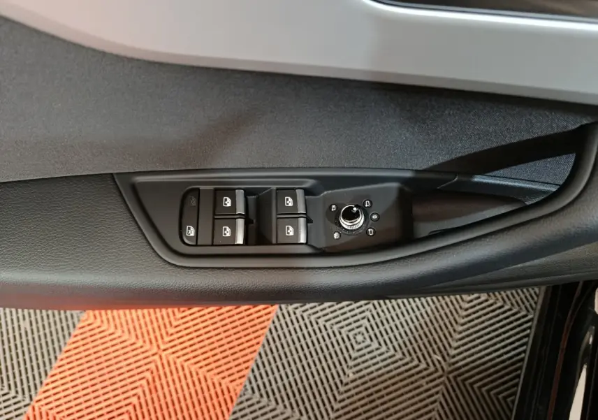 Vue rapprochée du panneau de commandes des vitres et rétroviseurs côté gauche d’une Audi A4 noire 2024.