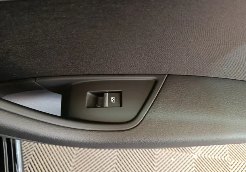 Détail du bouton de lève-vitre noir sur la porte intérieure côté gauche d'une Audi A4 35 TFSI 2024 noire.