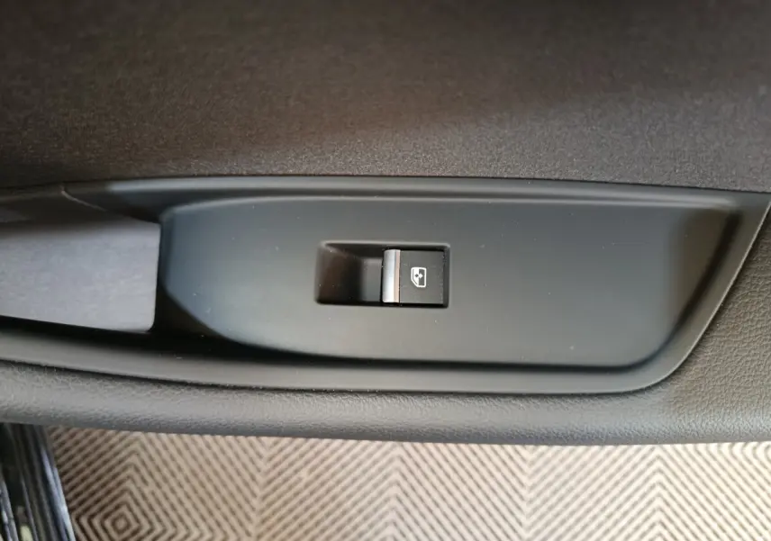 Gros plan sur l'interrupteur de lève-vitre côté gauche de l'Audi A4 noire 2024, finition Business Line.