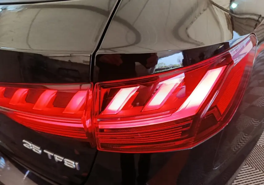 Gros plan sur le feu arrière droit rouge d'une Audi A4 35 TFSI noire, soulignant le badge du modèle.