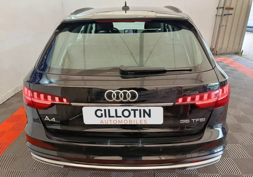 Vue arrière d'une Audi A4 35 TFSI noire, avec feux LED allumés et logo Audi bien visible.