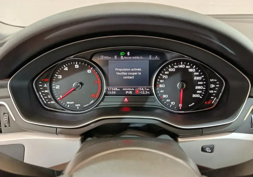 Vue rapprochée du tableau de bord numérique d'une Audi A4 35 TFSI 2024, affichage des compteurs et message d'arrêt.