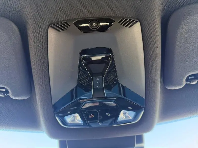 Détail du plafonnier intérieur noir brillant du MINI Countryman 2024, avec commandes lumineuses et bouton SOS visible.