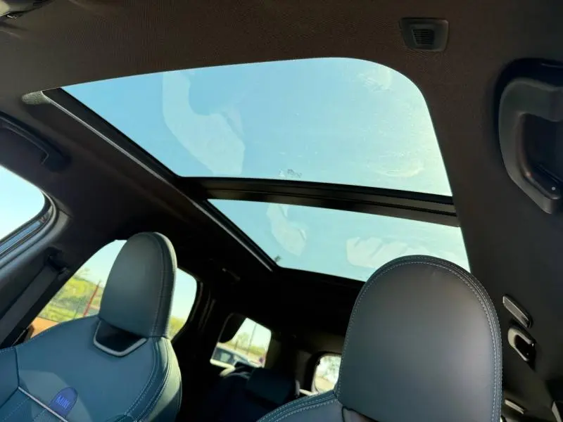 Vue intérieure du toit ouvrant panoramique du MINI COUNTRYMAN Midnight Black II 2024, avec sièges avant en cuir gris.