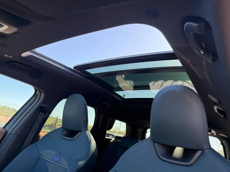 Vue intérieure du toit ouvrant panoramique et des sièges avant en cuir du MINI Countryman 2024 Midnight Black II.