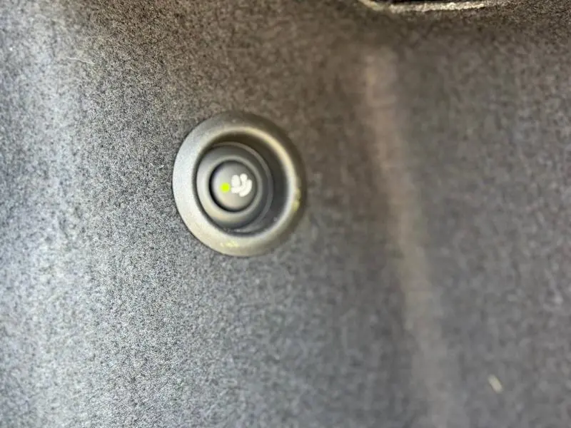 Bouton de déverrouillage intérieur du coffre du MINI COUNTRYMAN 2024 Diesel Hybride, détail sur fond gris.