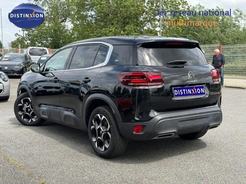 Vue 3/4 arrière droite d'un Citroën C5 Aircross 2024 noir Perla Nera avec jantes alu et feux arrière LED distinctifs.