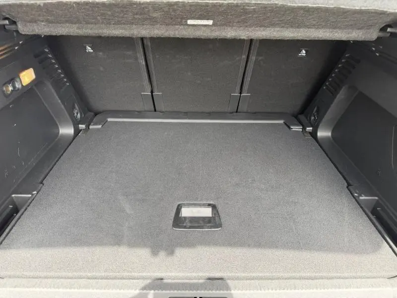 Coffre ouvert vu de l'arrière du Citroën C5 Aircross noir avec plancher de coffre mobile et habillage intérieur noir.
