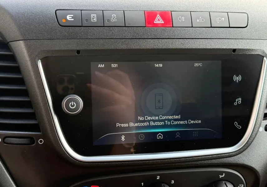 Gros plan sur l'écran tactile et la rangée de boutons du tableau de bord du fourgon Iveco Daily 2026, intérieur noir.