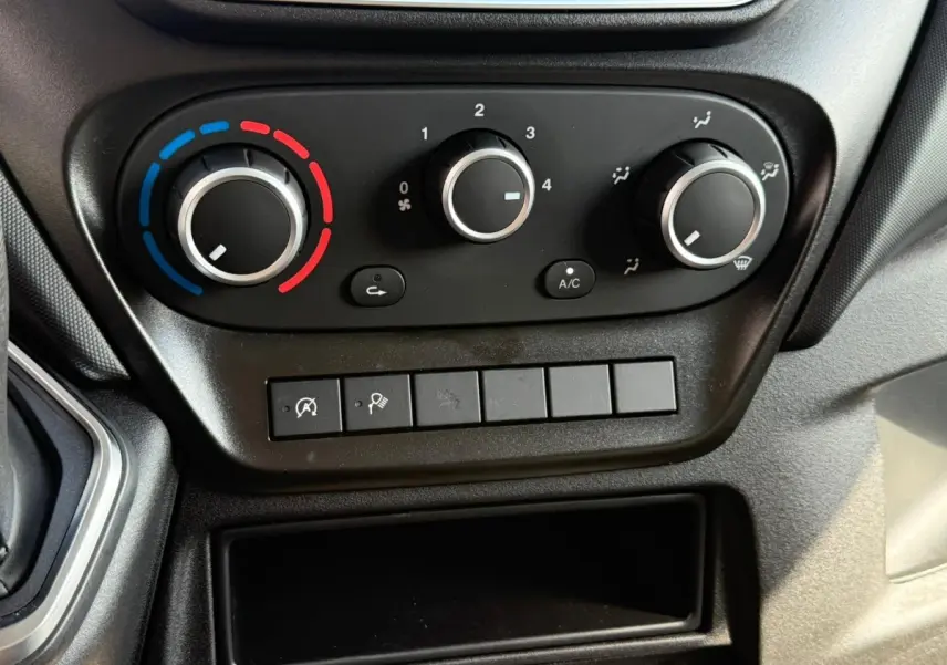 Détail du tableau de bord du Iveco Daily 2026 montrant les commandes de climatisation et les boutons de fonction en plastique noir.